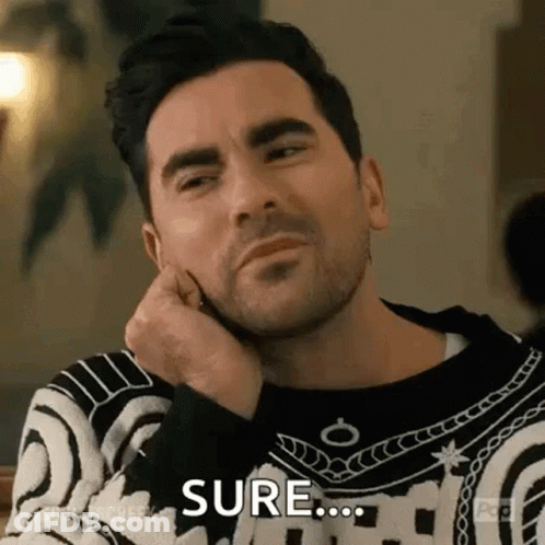 A Man With A Beard Is Sitting At A Table With His Hand On His Chin And Making A Funny Face . GIF