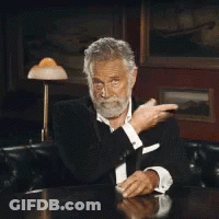 A Man With A Beard Is Sitting At A Table With His Hands Up GIF