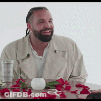 A Man With A Beard Is Sitting At A Table With Red Roses And A Glass Of Water GIF