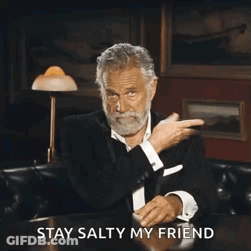 A Man With A Beard Is Sitting At A Table With The Words " Stay Salty My Friend " Written Below Him GIF