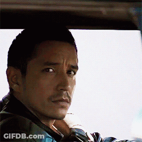 A Man With A Beard Is Sitting In A Car And Looking Out The Window GIF