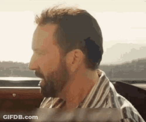 A Man With A Beard Is Sitting In A Car With His Eyes Closed . GIF