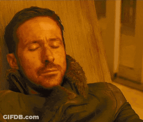 A Man With A Beard Is Sitting In A Chair And Looking At The Camera GIF