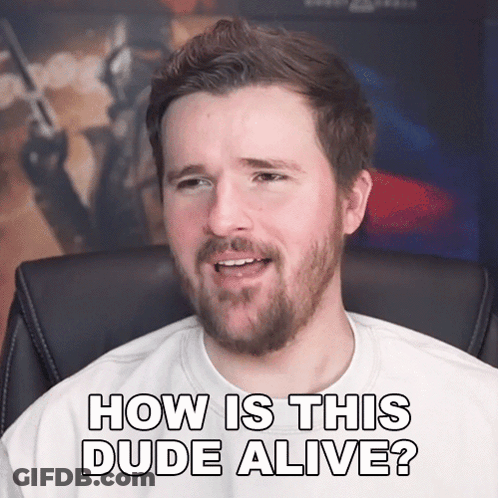 A Man With A Beard Is Sitting In A Chair And Says How Is This Dude Alive GIF