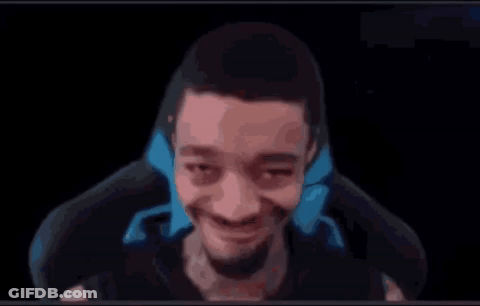 A Man With A Beard Is Sitting In A Chair And Smiling At The Camera . GIF