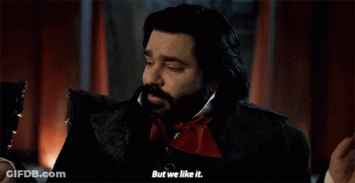 A Man With A Beard Is Sitting In A Chair And Talking To Another Man . GIF