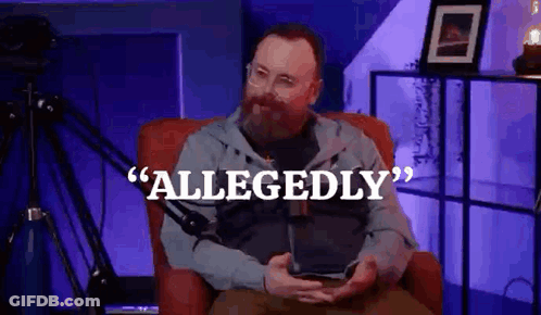 A Man With A Beard Is Sitting In A Chair In Front Of A Microphone Holding A Tablet . GIF