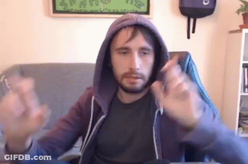 A Man With A Beard Is Sitting In A Chair Wearing A Hoodie And Making A Funny Face . GIF