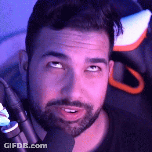 A Man With A Beard Is Sitting In A Chair With A Microphone In Front Of Him . GIF