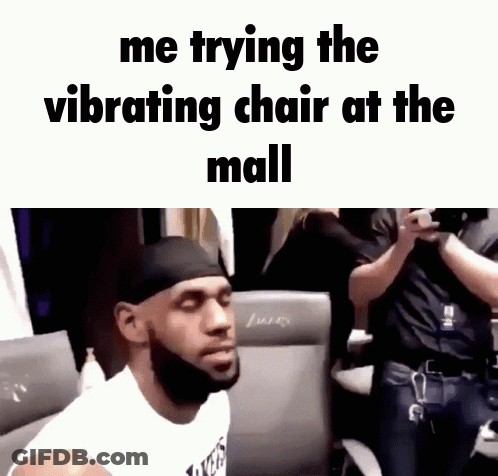 A Man With A Beard Is Sitting In A Chair With The Words Me Trying The Vibrating Chair At The Mall Above Him GIF