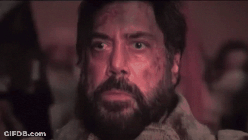 A Man With A Beard Is Sitting In A Dark Room And Looking Up At The Sky . GIF