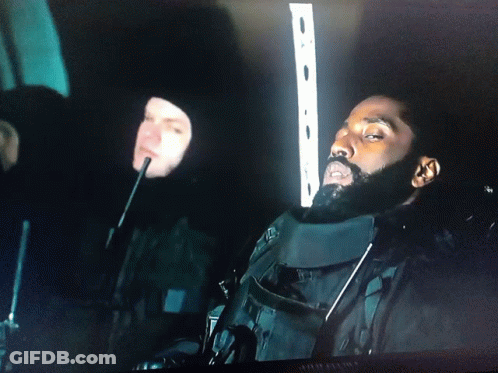 A Man With A Beard Is Sitting In A Dark Room Next To Another Man With A Microphone GIF