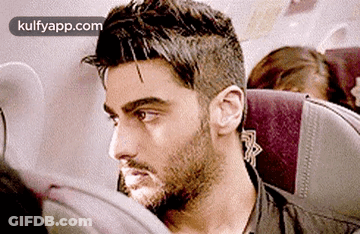 A Man With A Beard Is Sitting In An Airplane Seat . GIF