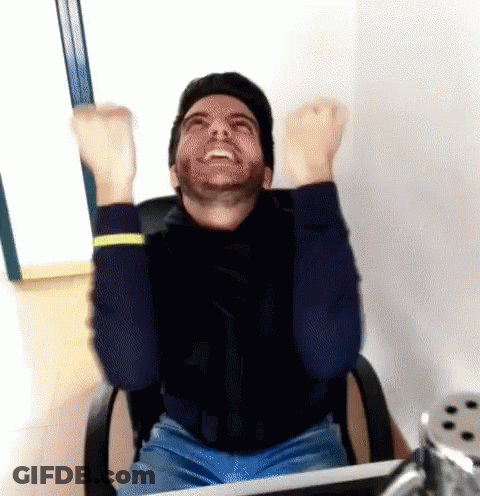 A Man With A Beard Is Sitting In An Office Chair With His Arms In The Air GIF