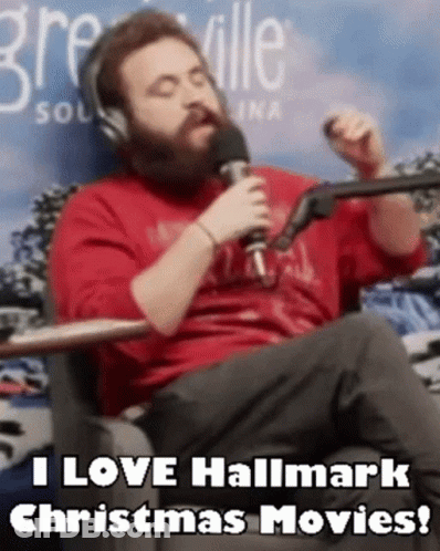 A Man With A Beard Is Sitting In Front Of A Microphone And Saying I Love Hallmark Christmas Movies . GIF