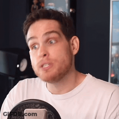 A Man With A Beard Is Sitting In Front Of A Microphone Making A Funny Face GIF