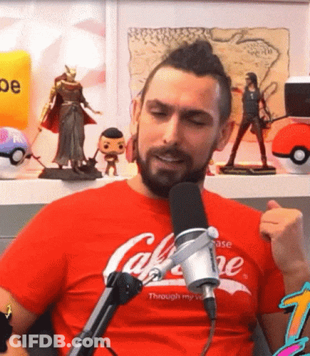 A Man With A Beard Is Sitting In Front Of A Microphone Wearing A Red T-Shirt That Says Coca-Cola GIF