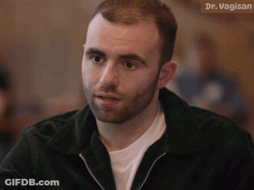 A Man With A Beard Is Sitting In Front Of A Sign That Says Dr. Vagin GIF