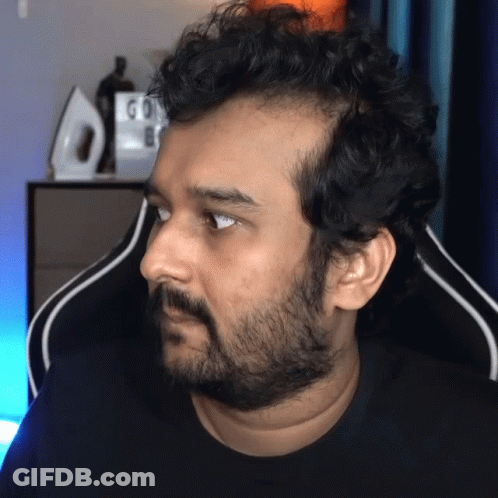 A Man With A Beard Is Sitting In Front Of A Sign That Says Go On GIF