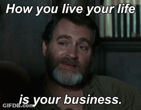 A Man With A Beard Is Sitting In Front Of A Sign That Says " How You Live Your Life Is Your Business " GIF