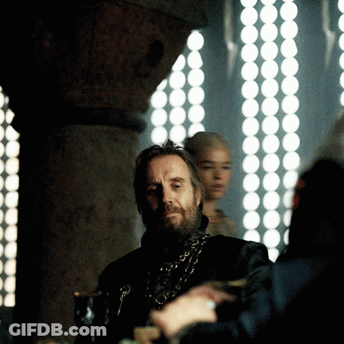 A Man With A Beard Is Sitting In Front Of A Window With Circles On It GIF