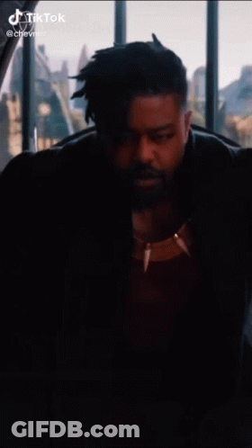 A Man With A Beard Is Sitting In Front Of A Window . GIF