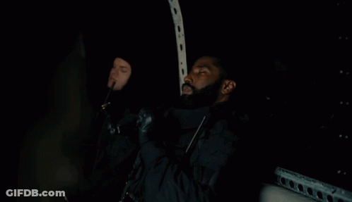 A Man With A Beard Is Sitting In The Dark Holding A Gun GIF