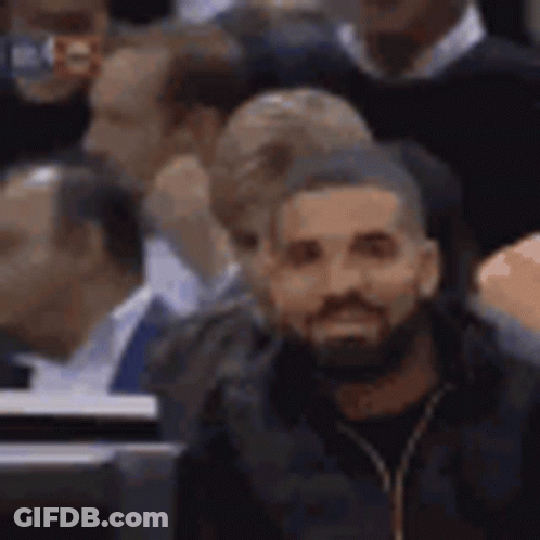 A Man With A Beard Is Sitting In The Stands At A Basketball Game . GIF