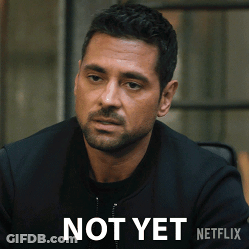 A Man With A Beard Is Sitting Next To A Sign That Says " Not Yet " GIF