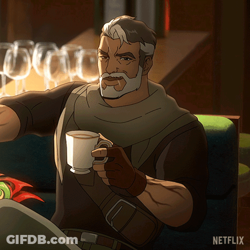 A Man With A Beard Is Sitting On A Couch Holding A Cup Of Coffee With A Netflix Logo In The Background GIF