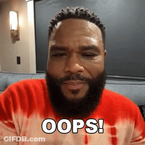 A Man With A Beard Is Sitting On A Couch Wearing A Red Tie Dye Shirt And Saying Oops . GIF