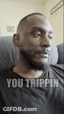A Man With A Beard Is Sitting On A Couch With The Words You Trippin On His Face GIF