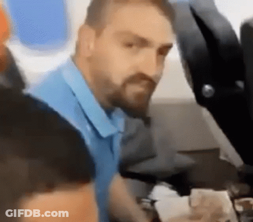 A Man With A Beard Is Sitting On A Plane Looking At Something . GIF