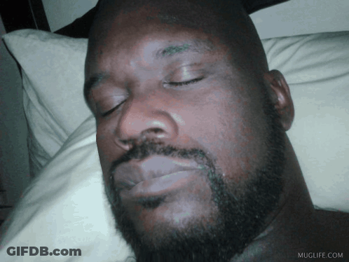 A Man With A Beard Is Sleeping On A Bed With Muglife.com Written On The Bottom Right GIF