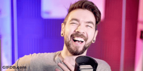 A Man With A Beard Is Smiling And Holding A Microphone GIF