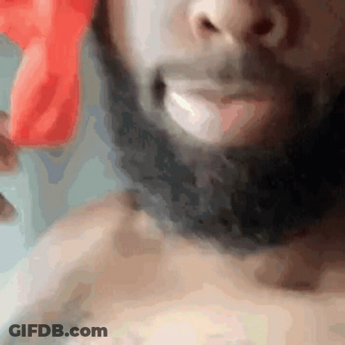 A Man With A Beard Is Smiling And Holding A Red Object In His Hand . GIF