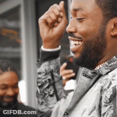 A Man With A Beard Is Smiling And Holding His Fist Up GIF