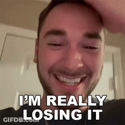 A Man With A Beard Is Smiling And Holding His Head . GIF