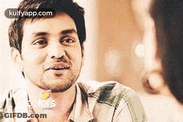 A Man With A Beard Is Smiling And Looking At A Woman . GIF