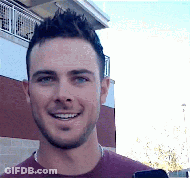 A Man With A Beard Is Smiling And Looking At The Camera GIF