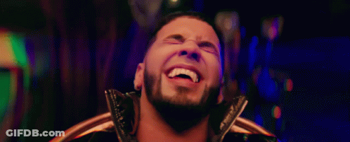 A Man With A Beard Is Smiling And Looking At The Camera GIF