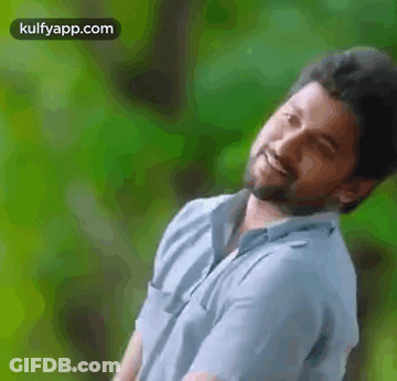 A Man With A Beard Is Smiling And Looking At The Camera . GIF