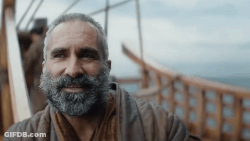 A Man With A Beard Is Smiling And Looking To The Side GIF