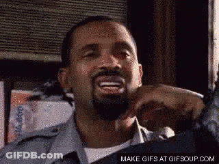 A Man With A Beard Is Smiling And Making A Funny Face With His Hands In The Air . GIF