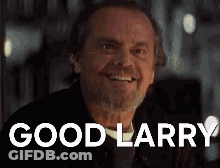 A Man With A Beard Is Smiling And The Words `` Good Larry '' Are On The Screen Behind Him . GIF
