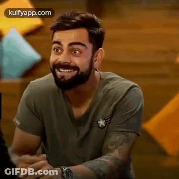 A Man With A Beard Is Smiling And Wearing A Watch While Sitting Down . GIF