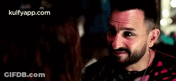 A Man With A Beard Is Smiling At A Woman In A Restaurant . GIF