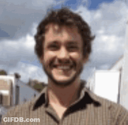 A Man With A Beard Is Smiling For The Camera GIF
