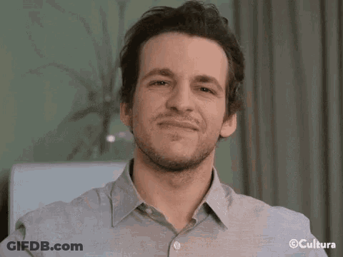 A Man With A Beard Is Smiling For The Camera . GIF