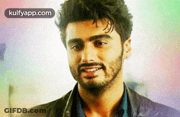 A Man With A Beard Is Smiling For The Camera . GIF